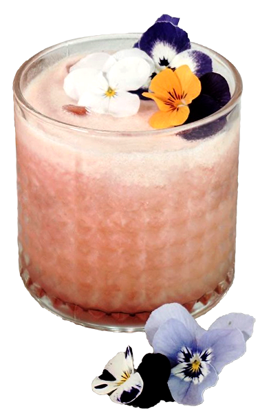 Guava coloured cocktail served in tumbler glass, garnished with edible flowers.
